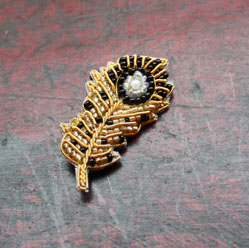 Broche en forme de plume réalisée en broderie d’or